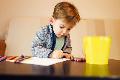 Boy making drawing on table at home