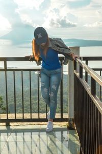 Woman standing by railing against sea