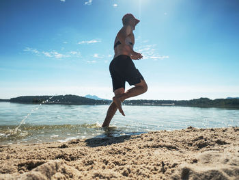 Sportsman running in water of lake in summer resort. man athlete checking pulse during workout run