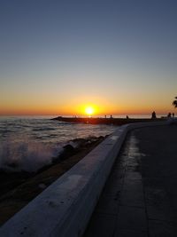 Scenic view of beach against clear sky during sunset