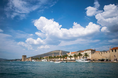 Buildings by sea against blue sky