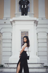 Full length portrait of woman standing against building