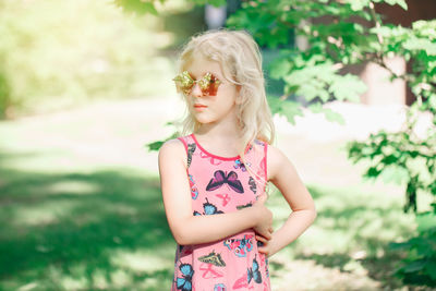 Young girl posing in fancy pink pentagonal shaped sunglasses outdoor. cool hipster gen z kid 