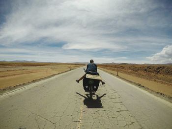 Rear view of woman riding bicycle on road