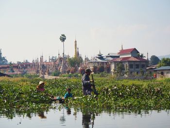 People by lake against buildings