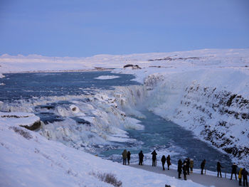 People on snow covered land against sky
