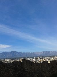 Aerial view of townscape and mountains against blue sky