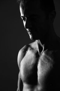 Close-up of shirtless man against black background