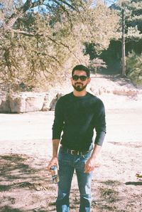 Full length portrait of young man standing against trees