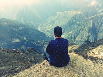 Rear view of man sitting on mountain