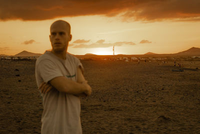 Side view of man standing at beach against sky during sunset