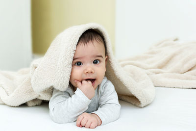 Portrait of cute baby girl lying on bed