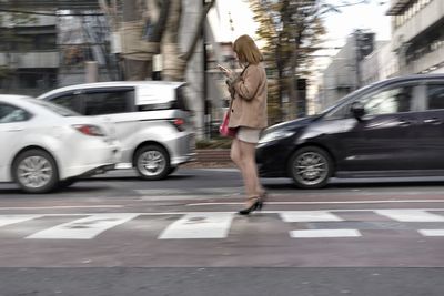Woman holding umbrella on street in city