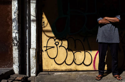 Rear view of man standing against graffiti wall