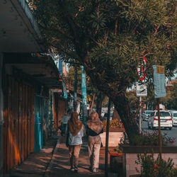 People standing by tree against building