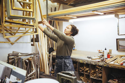 Confident young female artist holding frame at workshop