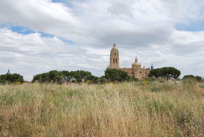 View of temple on field against cloudy sky