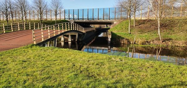 Bridge over river amidst field against sky