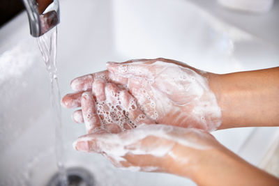 Cropped hand washing hands in sink