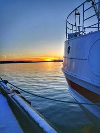 Boat moored in sea against sky during sunset