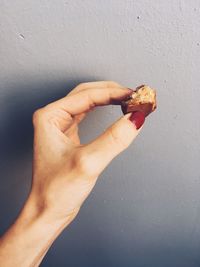 Close-up of hand holding ice cream against wall