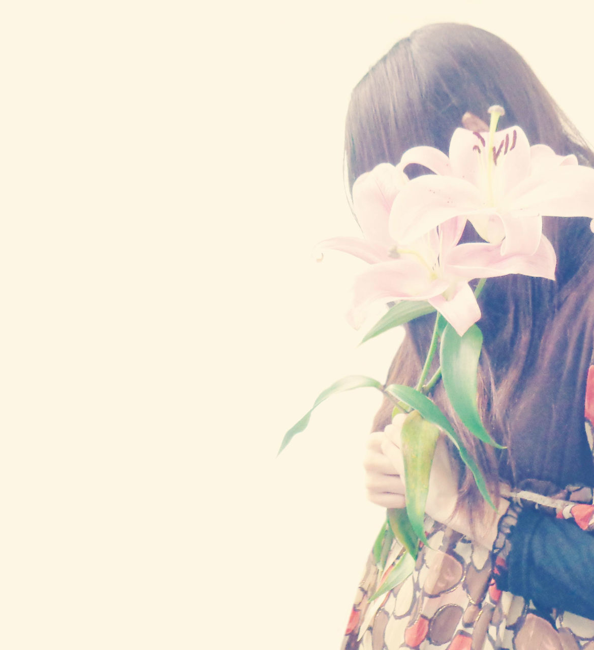 CLOSE-UP OF WOMAN HOLDING WHITE FLOWERING PLANT AGAINST GRAY BACKGROUND