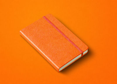 High angle view of paper on table against orange background