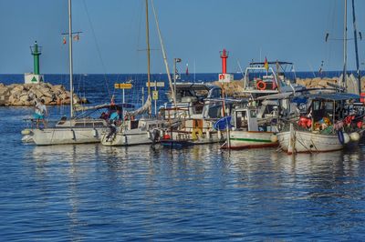 Boats moored at harbor against clear sky