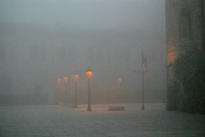 Illuminated street light against sky during foggy weather