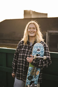 Portrait of smiling teenage girl holding skateboard