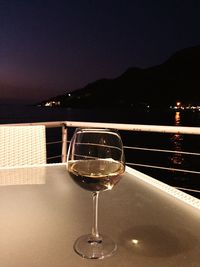 Close-up of wine glasses on table against clear sky at night