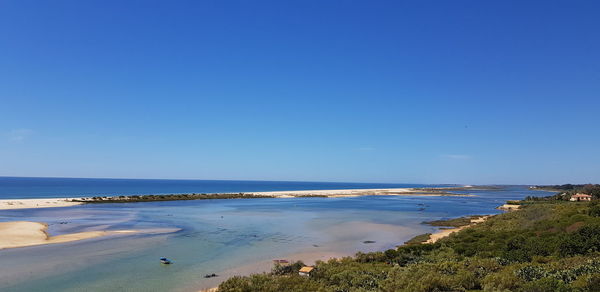 Scenic view of beach against clear blue sky