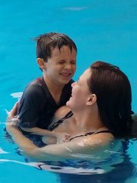 Side view of mother and daughter swimming in pool