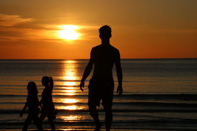 Silhouette people on beach during sunset