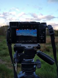 Close-up of camera on field against sky