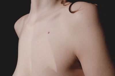 Rear view of shirtless woman against black background