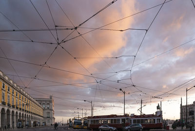 Cars on bridge in city against sky at sunset