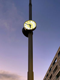 Low angle view of clock on pole against building