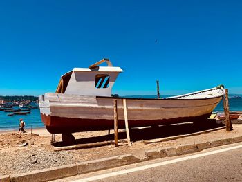 Ship moored on beach against clear blue sky