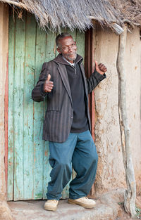 Portrait of mature man standing outside hut