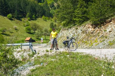 People riding bicycle on road amidst trees