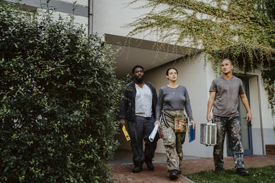 Confident female construction manager walking with workers outside house