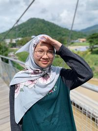 Portrait of smiling girl wearing hijab standing on footbridge