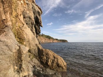 Scenic view of sea by cliff against sky