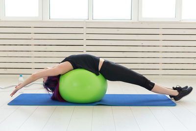 Midsection of woman with vegetables on floor against window