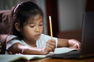 Close-up of girl studying on table at home
