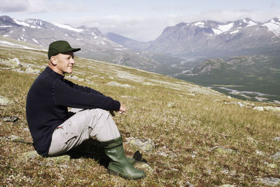 Side view of smiling man sitting on mountain