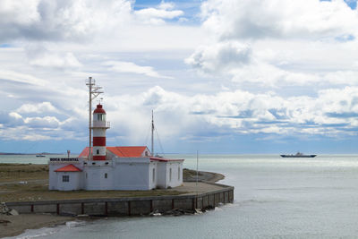 Lighthouse by sea against sky