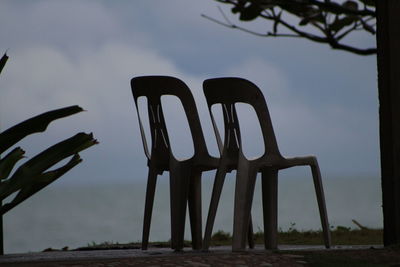 Low angle view of silhouette chair against sky