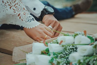 Close-up of couple holding hands by white flower bouquet